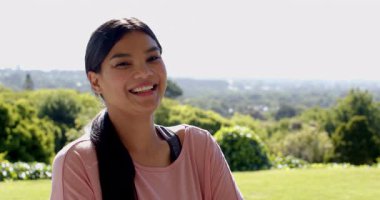 Güler yüzlü kadın yemyeşil parkta güneşli bir günün tadını çıkarıyor. Doğa, rahatlık, rahatlama, mutluluk, sağlık, yaz.