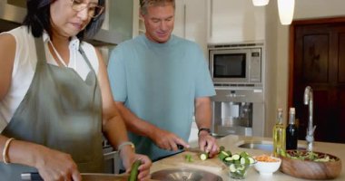 Üst düzey çeşitli çiftler modern mutfakta birlikte yemek hazırlıyorlar, evde yemek pişirmenin tadını çıkarıyorlar. Mutfak, takım çalışması, malzemeler, olgun, yaşam tarzı, bağ.