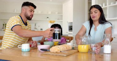 Aile kahvaltıda birlikte eğleniyor, kahve ve portakal suyu dolduruyor. Aile zamanı, sabah rutini, mutfak, içecekler, yaşam tarzı, toplanma