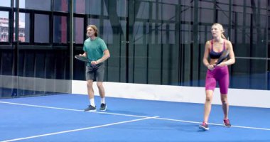 Kapalı sahada Padel tenis oynayan, oyuna ve takım çalışmasına odaklanan kadınlar. Spor, aktif, eğlence, rekabet, raket, eğlence