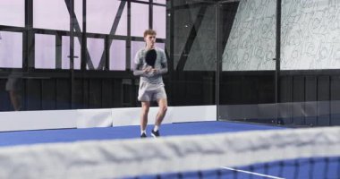 Kapalı alanda Padel tenis oynayan genç adam, geri dönen topa odaklanıyor, kapalı sahada. Sporcu, raket, raket, iç saha, yarışma, spor