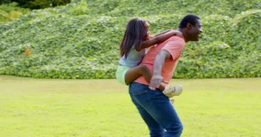 Afrikalı Amerikalı, babası kızı parkta sırtında taşıyor açık hava eğlencesinin tadını çıkarıyor, fotokopi çekiyor. Aile, bağ, eğlence, babalık, çocukluk, açık hava.