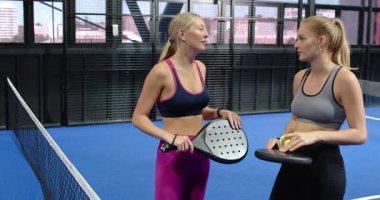 Kapalı alanda Padel tenis kortunda kadınlar gülüyor ve kürek çekiyor. Spor, takım çalışması, aktif, boş zaman, raket, egzersiz