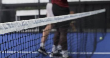 Kapalı alanda tenis oynayan iki farklı adam oyun stratejisine odaklanıyor. Spor, takım çalışması, rekabet, raket, fitness, çeşitli sporcular