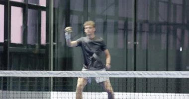 Padel tenisi oynayan genç adam, kapalı sahada hizmet etmeye hazırlanıyor. Spor, raket, fitness, aktivite, erkek, konsantrasyon