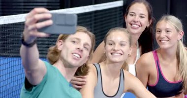 Bir grup genç yetişkin kapalı sahada oturmuş birlikte Padel tenis stratejisini tartışıyorlar. Spor, takım çalışması, aktif, tartışma, raket, fitness