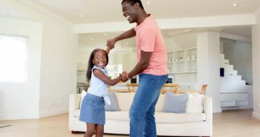 Afrikalı Amerikalı, baba ve kız oturma odasında dans ediyor, birlikte mutlu anları paylaşıyorlar. aile, babalık, bağlılık, mutluluk, kutlama, dans