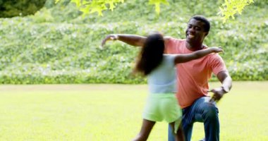 Afrikalı Amerikalı, baba kızıyla parkta oynuyor, hem gülüyor hem de güneşli günün tadını çıkarıyor, fotokopi çekiyor. Aile, bağ, açık hava, mutluluk, eğlence, babalık.