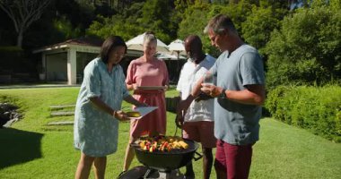 Çeşitli yaşlılar bahçe barbeküsünde ızgara sebze ve mısır yiyor. Bahçede, piknikte, yemeklerde, emeklilikte, tatilde