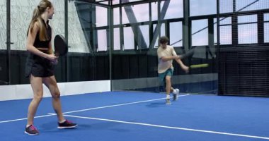 Mavi iç sahada Padel tenis oynayan genç adam topa vurmaya hazırlanıyor. Spor, aksiyon, turnuva, atletizm, yarışma, raket