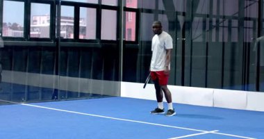 Padel tenis oynayan, raket tutan ve kapalı sahada gülümseyen bir adam. spor, atletik, aktif, rekabet, eğlence, egzersiz