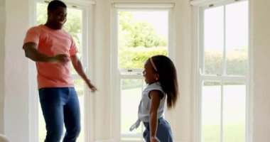 Afro-Amerikan, baba-kız evlerinde neşeyle dans ediyor, neşeli kaynaşma zamanlarının tadını çıkarıyor. Aile, mutluluk, dans, ilişki, etkinlik