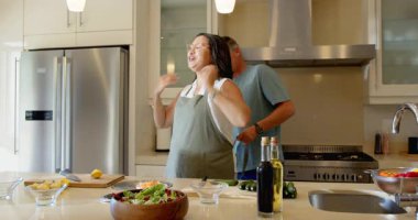 Üst düzey bir çift modern mutfakta taze salata hazırlıyor, evde yemek pişirmenin keyfini çıkarıyorlar. Olgun, aşçı, malzemeler, yaşam tarzı, yemek, sebze