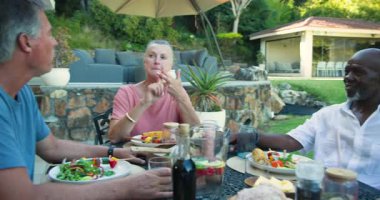 Farklı kıdemli arkadaşlar bahçede birlikte yemek yiyor, kahkahalarını ve lezzetli yemeklerini paylaşıyorlar. Arkadaşlık, toplanma, kutlama, yemek, mutfak, kaynaşma