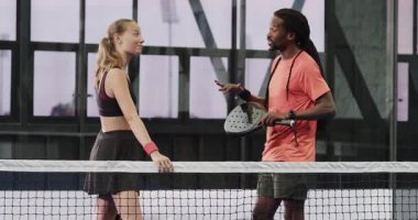 Padel 'in çeşitli oyuncuları sahada strateji tartışıyor, raket tutuyor, takım çalışması gösteriyor. Spor, raket, antrenörlük, işbirliği, oyun planı