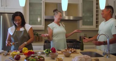 Çeşitli arkadaşlar birlikte sağlıklı yemekler hazırlıyor, modern mutfakta gülüyorlar. Aşçılık, arkadaşlık, yaşam tarzı, aşçılık, takım çalışması, sağlıklı beslenme