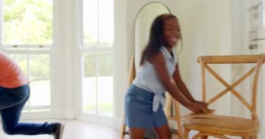 Afro-Amerikan, baba kızına ayakkabılar için şakacı bir şekilde yardım ediyor, ikisi de evde gülümsüyor. Aile, bağlılık, ebeveynlik, birliktelik, babalık, gündelik ilişkiler.