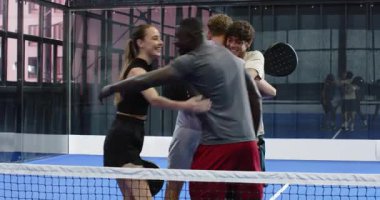 Çeşitli arkadaşlar tenis maçının keyfini çıkarıyorlar, sahada, kapalı sahada gülüp sohbet ediyorlar. Spor, raket, rekabet, eğlence, eğlence, açık hava