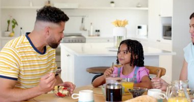 Aile kahvaltıdan keyif alıyor, sohbet ediyor ve gülümsüyor. Bağlanma, birliktelik, sabah, gündelik, mutluluk, mutfak