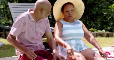 Yaşlı çift bahçede güneşli bir günün tadını çıkarıyor, rahatlıyor ve birlikte içkilerini yudumluyorlar. Son sınıf, rahatlama, rahatlama, yaşam tarzı, tatil, arkadaşlık.