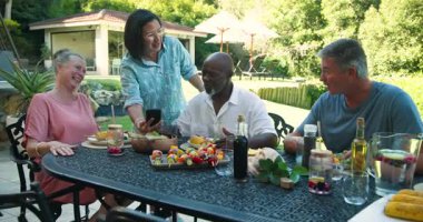 Kahkahalar, farklı kıdemli arkadaşlar, sağlıklı yiyeceklerle bahçede öğle yemeği. Arkadaşlık, kıdemli yaşam tarzı, yemek, çok nesilli, bahçede, sağlıkta