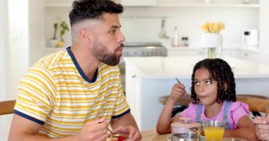 Afro-Amerikan ailesi, modern ve aydınlık mutfakta birlikte kahvaltı yapıyorlar. Aile zamanı, birliktelik, mutluluk, yaşam tarzı, bağlanma, sabah rutini