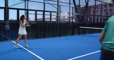 Kapalı sahada Padel tenis oynayan bir adam, topa güçlü bir şekilde vuruyor. spor, atlet, yarışma, fitness, hareket, aktivite