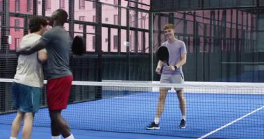 Padel kortunda iki farklı adam yoğun maçtan sonra raket tutuyorlar. Spor, rekabet, takım çalışması, egzersiz, arkadaşlık, aktif yaşam tarzı