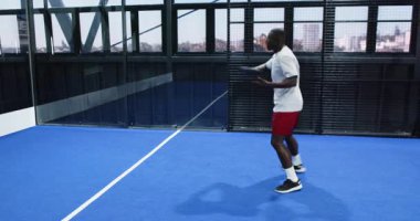 Mavi kapalı sahada Padel tenis oynayan bir adam, top oynamaya hazırlanıyor. Spor, raket, yarışma, atletizm, konsantrasyon, açık hava