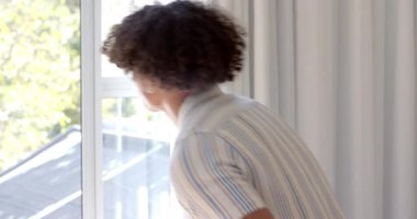 Kıvırcık saçlı genç adam pencereden dışarı özenle bakıyor. Düşünce, içgözlem, yalnızlık, rahatlama, dalgın, yaşam tarzı