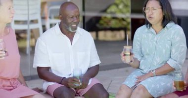 Kıdemli çeşitli arkadaşlar bahçede içkileri ve kahkahaları paylaşıyor, sohbet etmekten keyif alıyorlar. Arkadaşlık, birliktelik, bağlanma, yaşam tarzı, eğlence, içecekler.