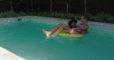 Havuzda rahatlarken, çeşitli çiftler şişme suda güneşli bir günün tadını çıkarıyorlar. Tatil, tatil, rahatlama, yaz, yüzme, birliktelik.