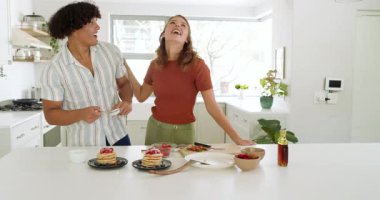 Mutfakta, çeşitli çiftler ev yapımı çilekli krep yiyorlar, evde birlikte gülümsüyorlar. Kahvaltı, aşçılık, birliktelik, yemek, mutluluk, yemek zamanı.