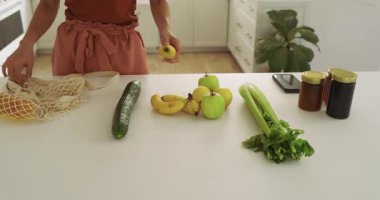 Mutfaktaki kadın tekrar kullanılabilir poşetlerde yiyecek düzenliyor, sürdürülebilir yaşamı kucaklıyor. Sürdürülebilirlik, çevre dostu, yeniden kullanılabilirlik, yaşam tarzı, çevre, organizasyon