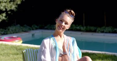 Çeşitli çiftler havuz başında güneşli bir günün tadını çıkarıyor, gülümsüyor ve neşeli sohbetler ediyorlar. Tatil, rahatlama, mutluluk, arkadaşlık, boş zaman, havuz başı