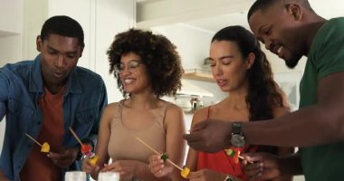 Çeşitli arkadaşlar mutfakta birlikte meyve şişi yapmaktan zevk alıyorlar, evde kahkaha ve neşe paylaşıyorlar. Aşçılık, arkadaşlık, aşçılık, bağlanma, işbirliği, eğlence