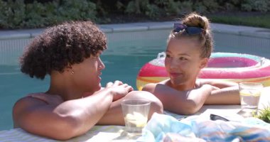 Güneşli bir günde havuz başında ferahlatıcı içkilerle rahatlayan farklı çiftler. Tatil, dinlenme, tatil, yaz tatili, yüzme havuzu, mutluluk.