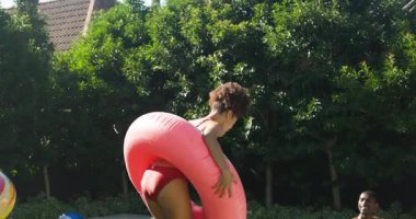 Çeşitli arkadaşlar şişme şamandıralar ve içkilerle havuz partisinden zevk alıyorlar, birlikte gülüyorlar. Yaz, havuz başı, eğlence, eğlence, rahatlama, kutlama