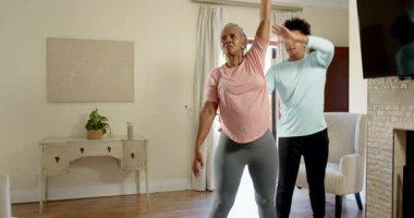 Yaşlı kadın ve genç adam evde birlikte egzersiz yapıyor, spor rutininin keyfini çıkarıyorlar. Egzersiz, egzersiz, birliktelik, sağlıklı yaşam tarzı, motivasyon, spor salonu.