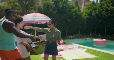 Farklı arkadaşlar havuz ve rengarenk havlularla piknik alanı hazırlıyorlar. Boş zaman, açık hava, yaz, toplanma, rahatlama, arkadaşlık.