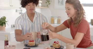 Çağdaş mutfakta çilekli krep ve kahvenin tadını çıkaran genç bir çift. Kahvaltı, yemek, yemek, brunch, yaşam tarzı, aşçılık