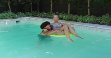 Havuzda dinlenen, şişme halkada yüzen neşeli çift, yaz gününün tadını çıkarıyorlar, fotokopi çekiyorlar. Boş zaman, tatil, yüzme, rahatlama, açık hava, eğlence.