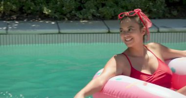 Afro-Amerikalı kadın renkli havuzda dinleniyor, güneşli günün tadını çıkarıyor. Tatil, tatil, rahatlama, yaz, yüzme, yaşam tarzı.