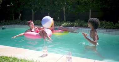 Çeşitli bayan arkadaşlar güneşli bir günde bilardo oynuyorlar, plaj topuyla oynuyorlar ve dinleniyorlar. Yaz, tatil, tatil, eğlence, yüzme, su sporları