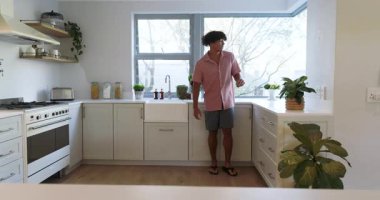 Mutfakta gülümseyen adam tezgaha yaslanıyor, evde rahat bir sabah geçiriyor. Yaşam tarzı, rahatlama, evcil, sabah rutini, sükunet, rahatlık.