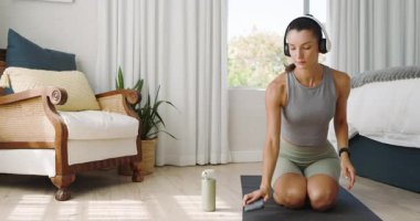 Evde yoga minderi üzerinde meditasyon yapan, kulaklık takan, kendini rahat hisseden bir kadın. Meditasyon, rahatlama, farkındalık, sağlık, sükunet, zen