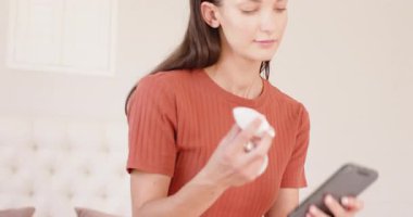 Woman comparing smart light bulbs using smartphone at home, making informed choice. Technology, smart home, lighting, innovation, decision-making, gadgets