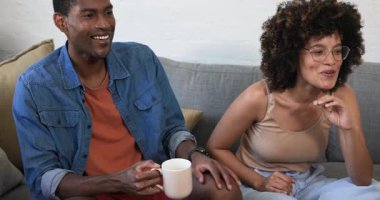 Çeşitli arkadaşlar evdeki rahat oturma odasındaki kanepede gülüp kahve içiyorlar. Arkadaşlık, kahkaha, rahatlama, bağlanma, içecek, soğutma