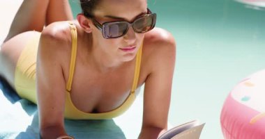 Güneş gözlüklü kadın havuzda dinleniyor, gülümsüyor ve güneşli günün tadını çıkarıyor. Tatil, tatil, rahatlama, güneşlenme, lüks, mutluluk.