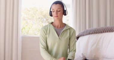 Kulaklık takan kadın evde dinleniyor, pencere kenarındaki huzurlu anın tadını çıkarıyor. Rahatlama, rahatlama, müzik, sükunet, konfor, yalnızlık